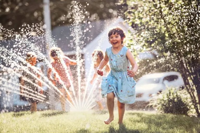 happy kids playing with garden sprinkler